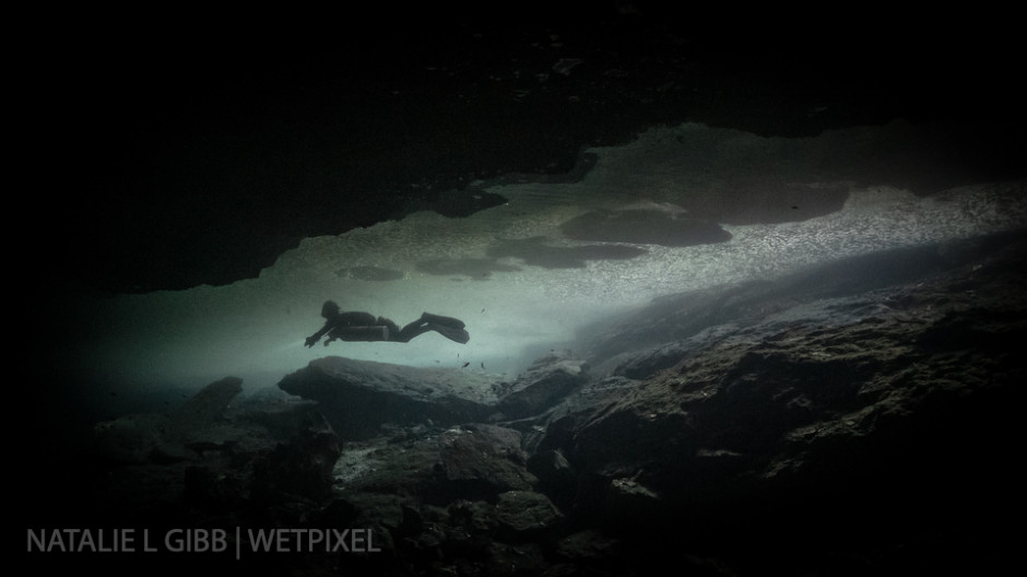 Diver Hana Cho swims beneath the surface of Cenote Lunas y Sombras. Calcite from the water creates a thin crust on the surface, and her exhaled bubbles mark her path.