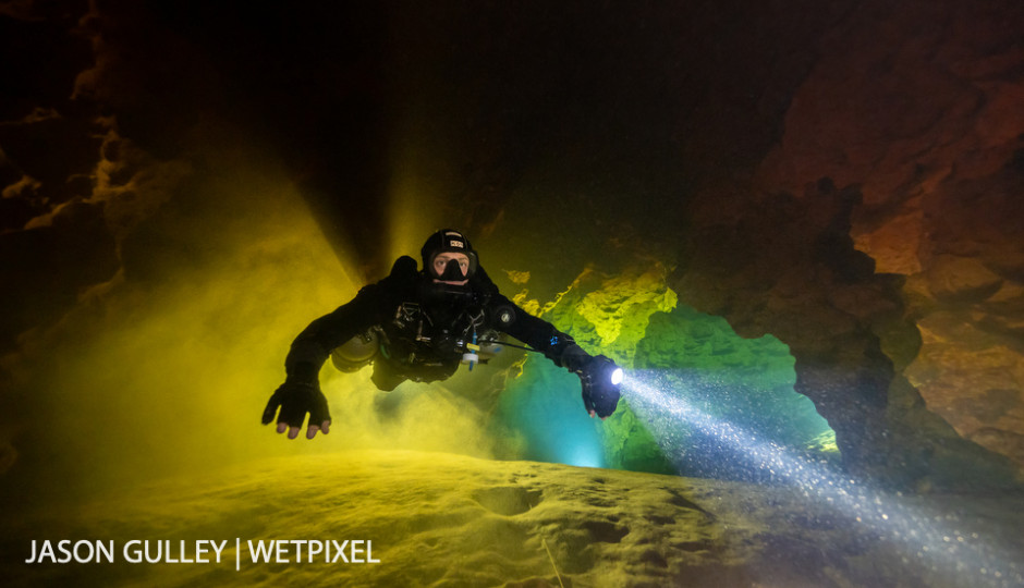 Cave diver Jaime De La Puerta Salazar fins through a layer of green-tinged groundwater sandwiched between tannic river water on the ceiling and the silty floor of Peacock Springs.