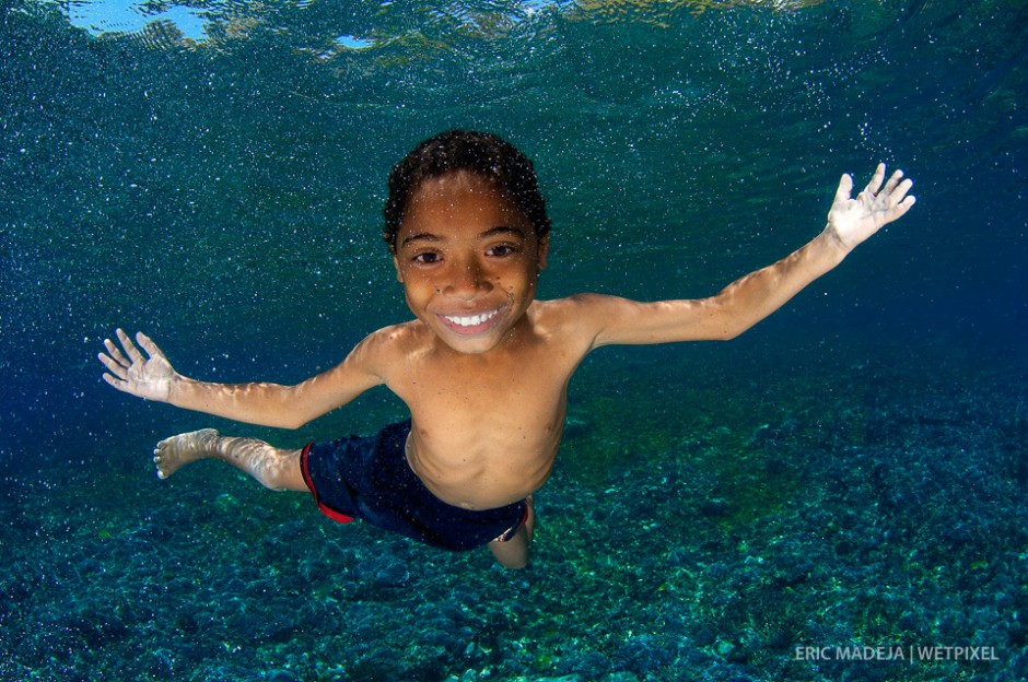 A young boy from Flores, Indonesia enjoying his own reflection in my cameras dome port. In the Coral Triangle, 141 million people live within 30km of a coral reef.
