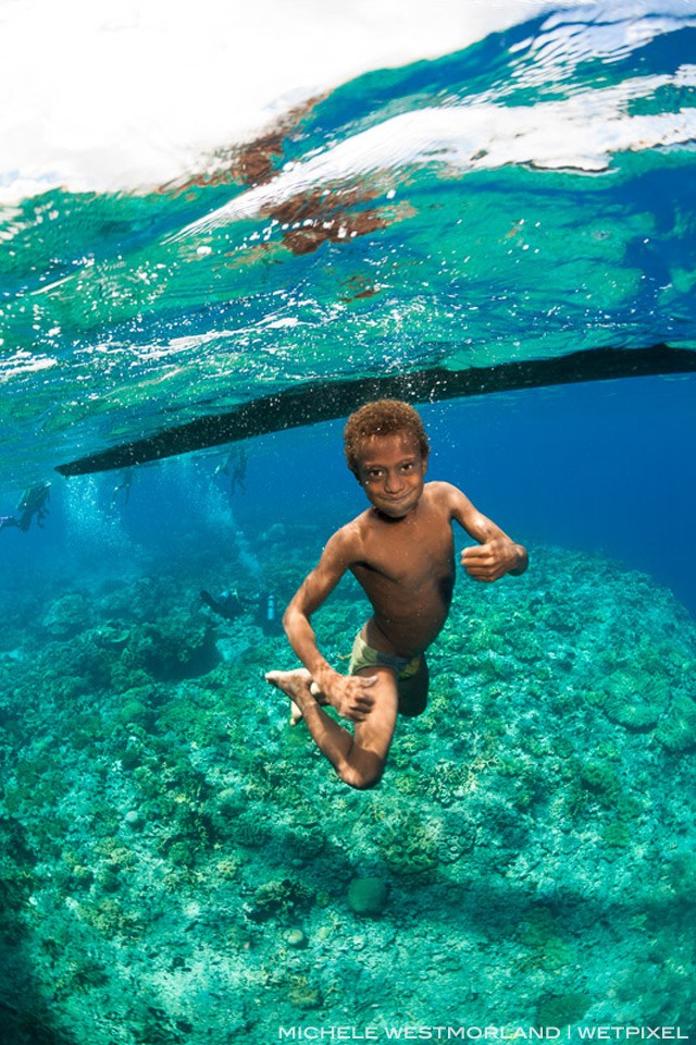 Young boy swimming under his canoe.  Witu Islands, Papua New Guinea